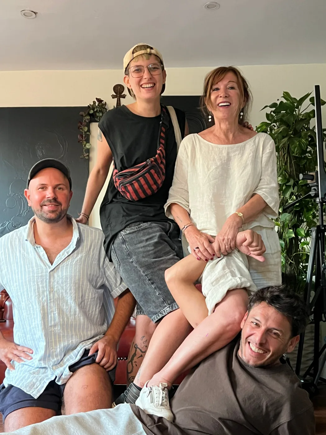 Five guests seated and standing together in the studio lounge beside a plant and studio lighting