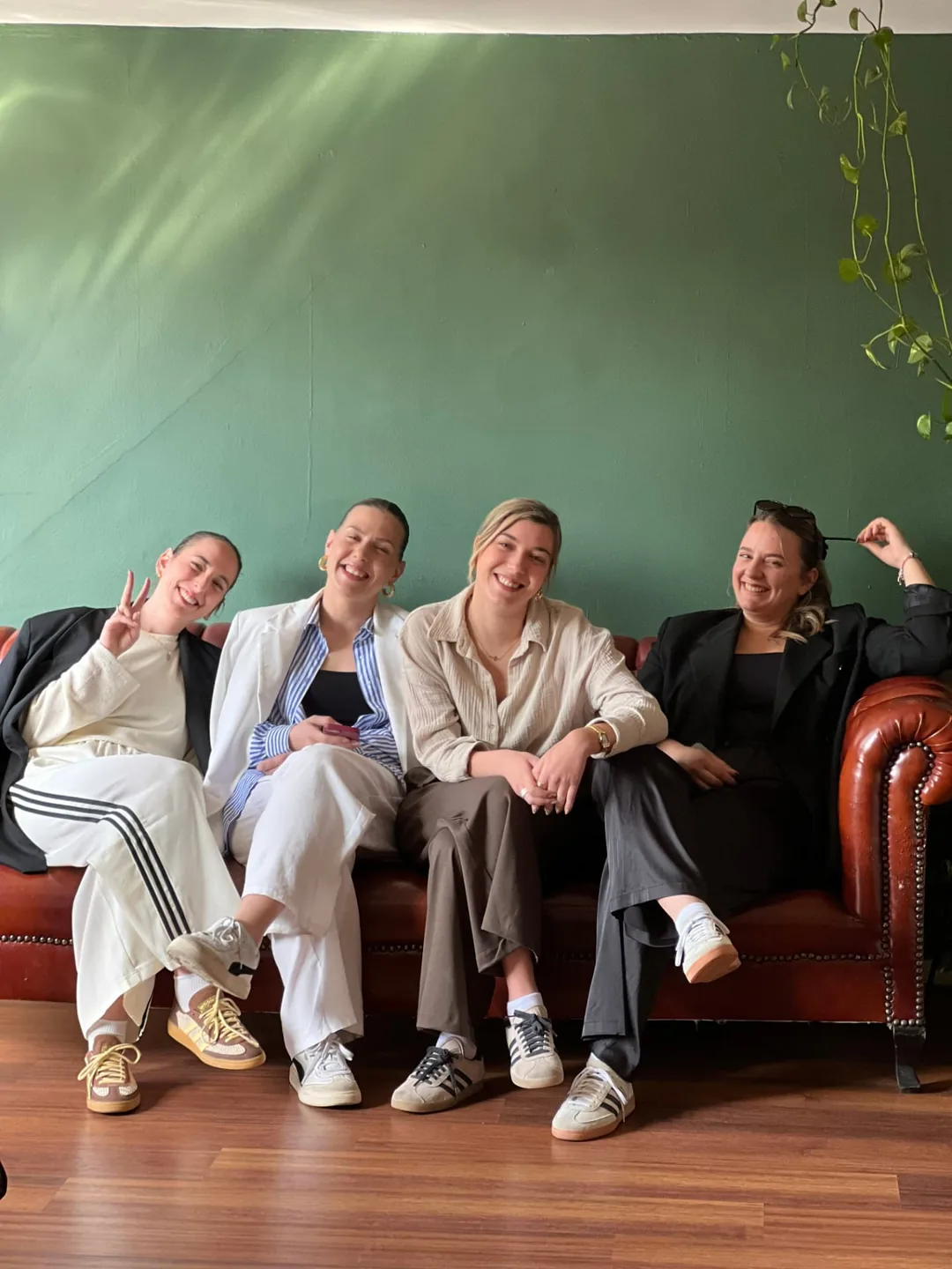 Four guests seated together on a leather sofa against a green wall inside the studio